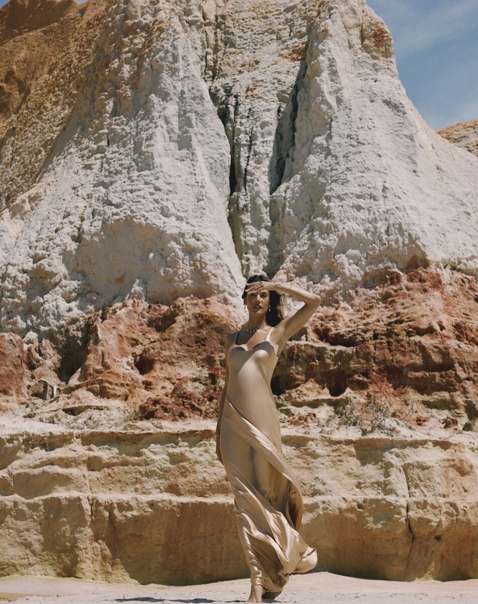 Alessandra Ambrosio em vestido acetinado dourado diante das falésias de Beberibe, no Ceará, na campanha Feitas de Luz da Morana