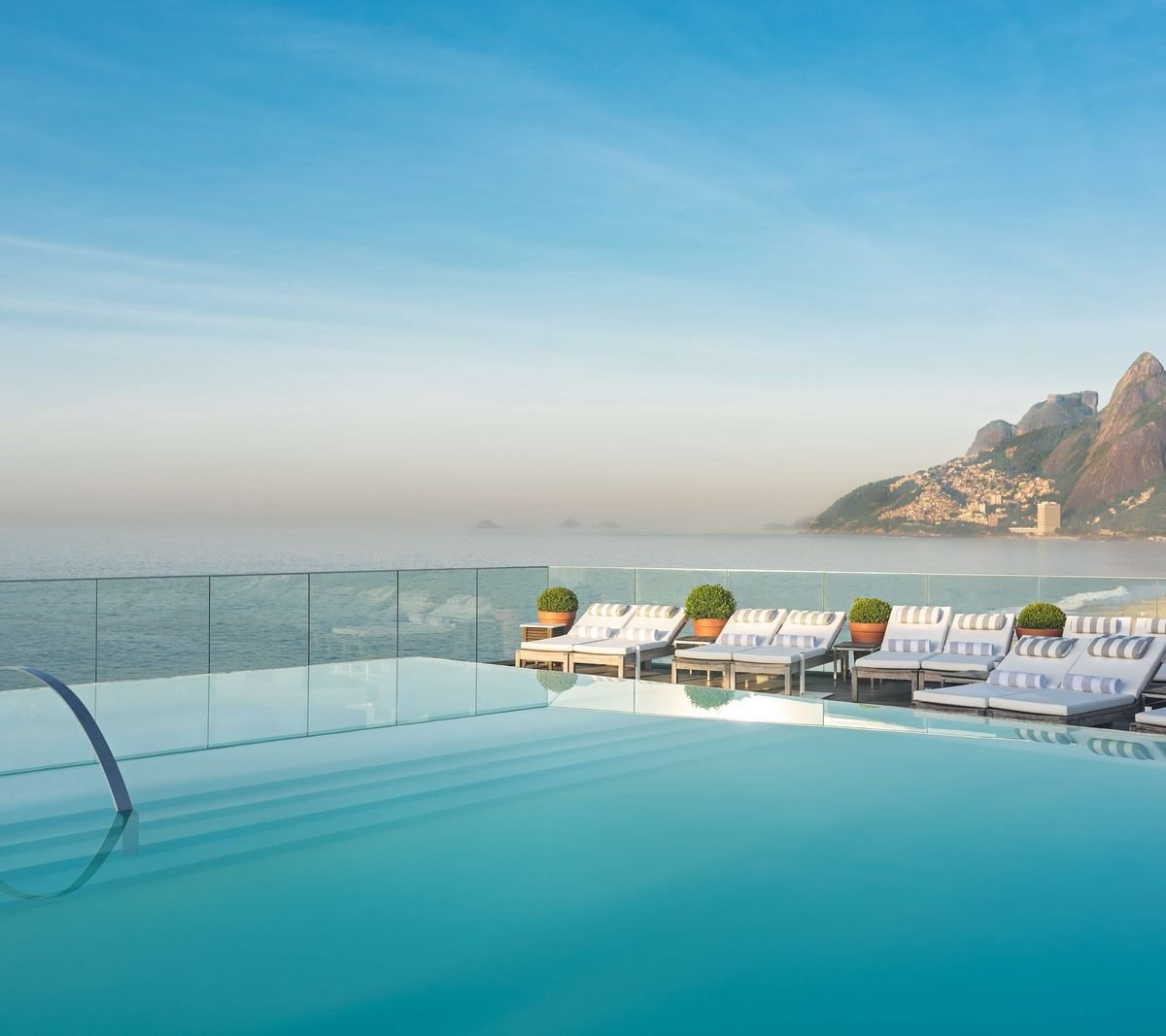 Piscina de borda infinita no rooftop do Fasano Rio de Janeiro, com a Praia de Ipanema e o Morro Dois Irmãos ao fundo
