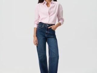 Modelo veste calça reta em jeans premium de cintura alta da Renner com camisa listrada rosa