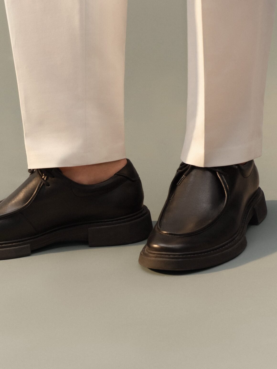 Black leather lace-up shoes by Ricardo Almeida worn with white tailored trousers