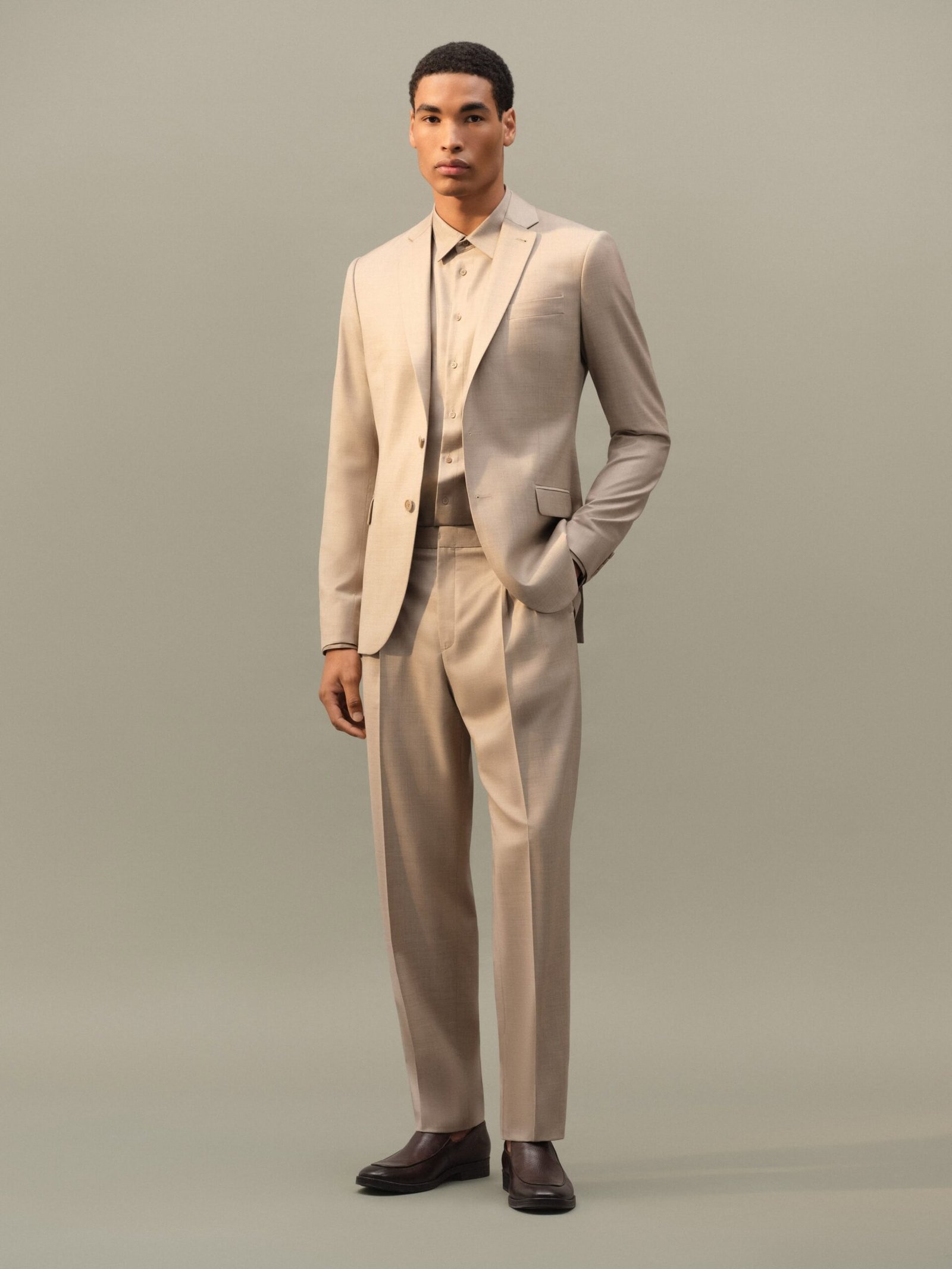 Model wearing a sand-toned Ricardo Almeida suit from the Summer 26/27 collection