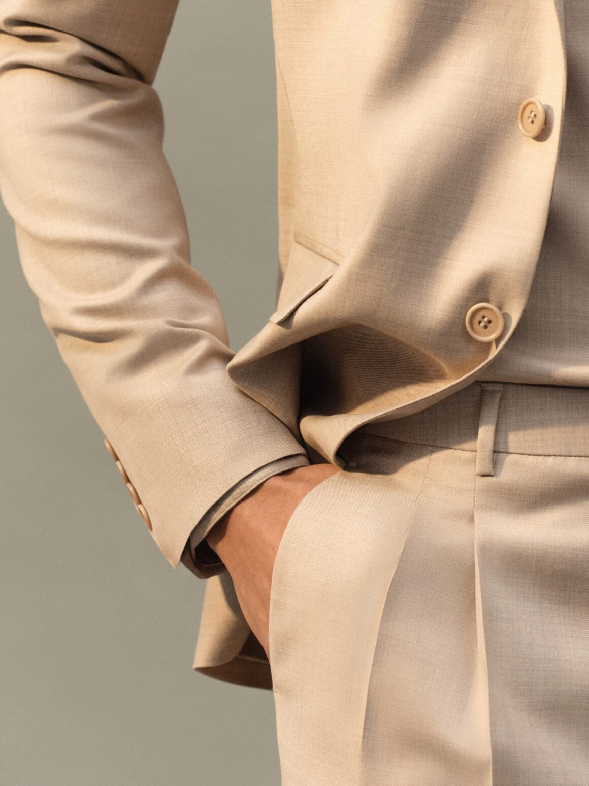 Close-up of a Ricardo Almeida tailored jacket in light cold wool, with hand in trouser pocket