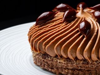 Doce de chocolate com mousse e gotas de caramelo servido em prato branco
