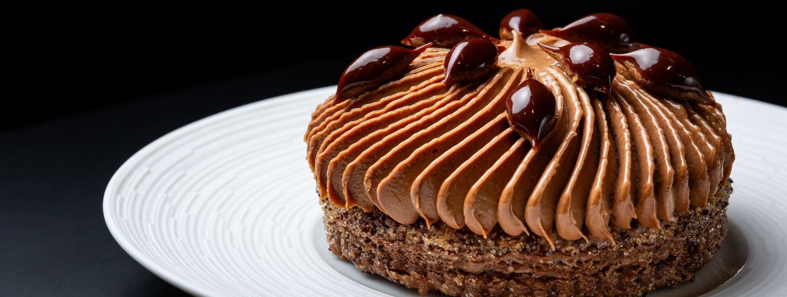 Doce de chocolate com mousse e gotas de caramelo servido em prato branco