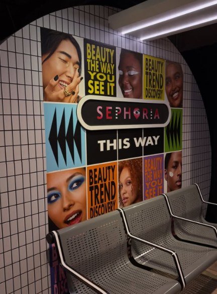 Painel da SEPHORiA London com retratos de maquiagem e o slogan Beauty the way you see it, ao lado de bancos metálicos