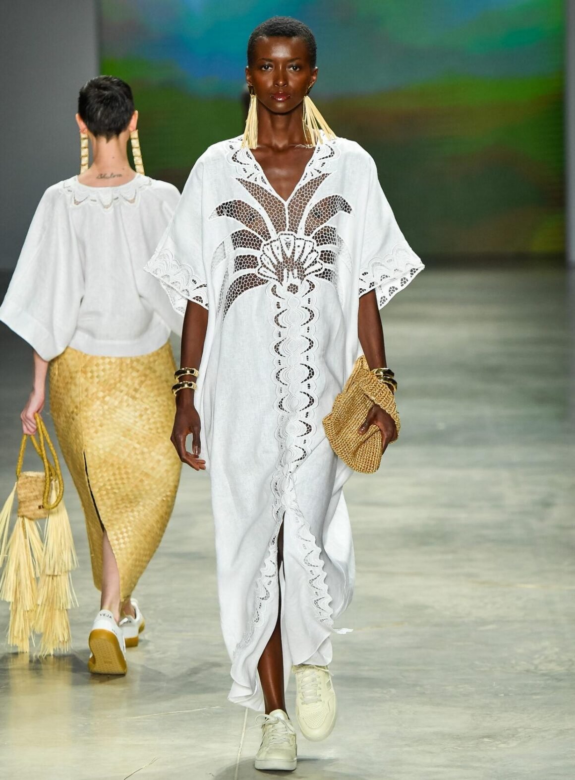 Modelo desfila com vestido longo de linho branco com bordado vazado e bolsa de palha, da Catarina Mina, no SPFW N61