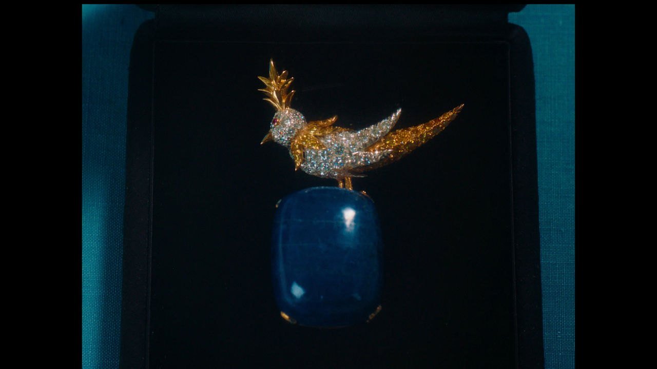 Broche de alta joalheria com pássaro de diamantes e ouro pousado sobre uma pedra azul