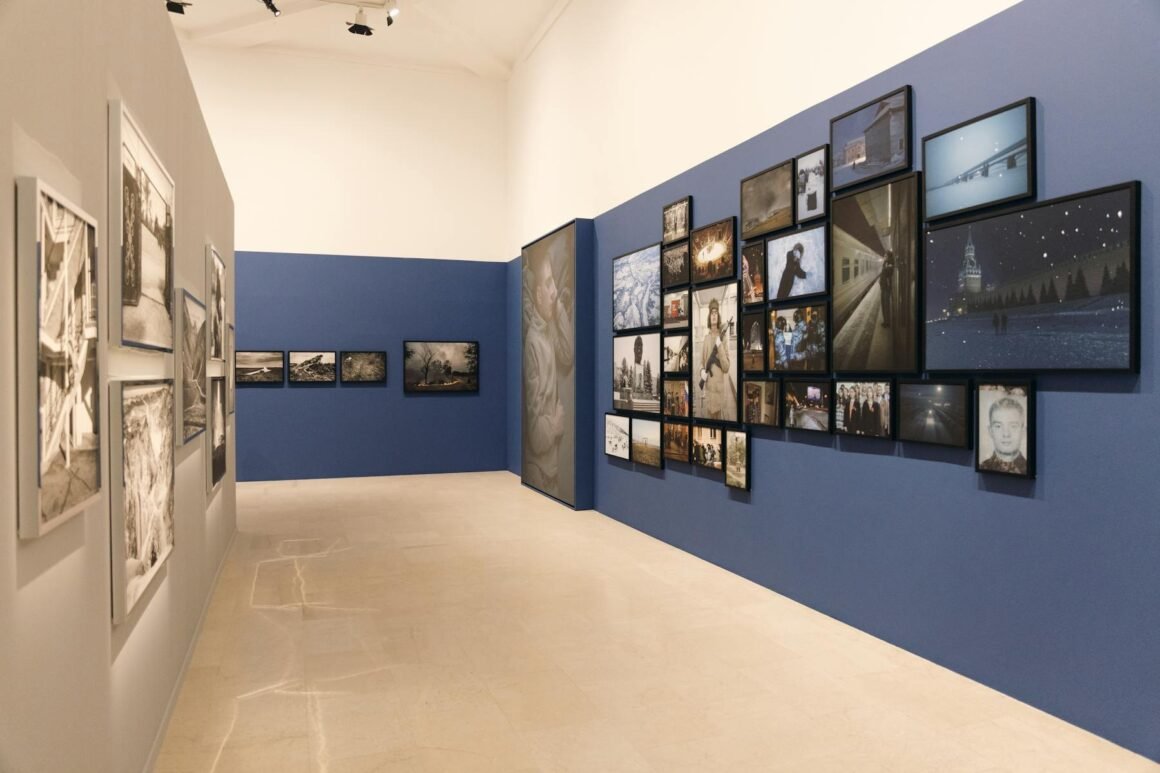 Vista da exposição do Photo Grant Deloitte na Triennale Milano, com fotografias emolduradas em paredes azuis e cinza