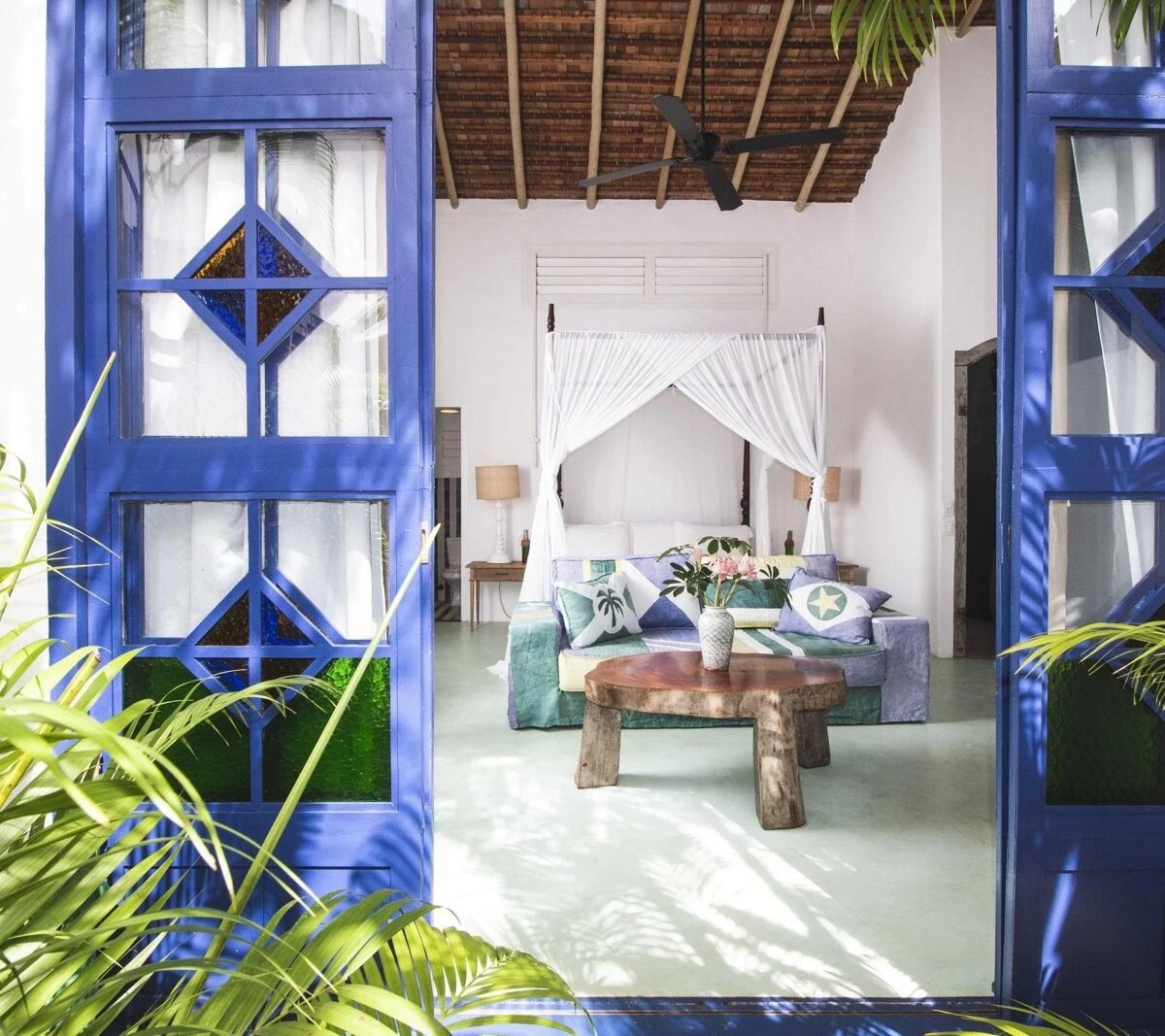 Blue wooden doors opening onto a guest house bedroom with a canopy bed at UXUA Casa Hotel & Spa in Trancoso