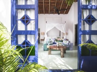 Blue wooden doors opening onto a guest house bedroom with a canopy bed at UXUA Casa Hotel & Spa in Trancoso